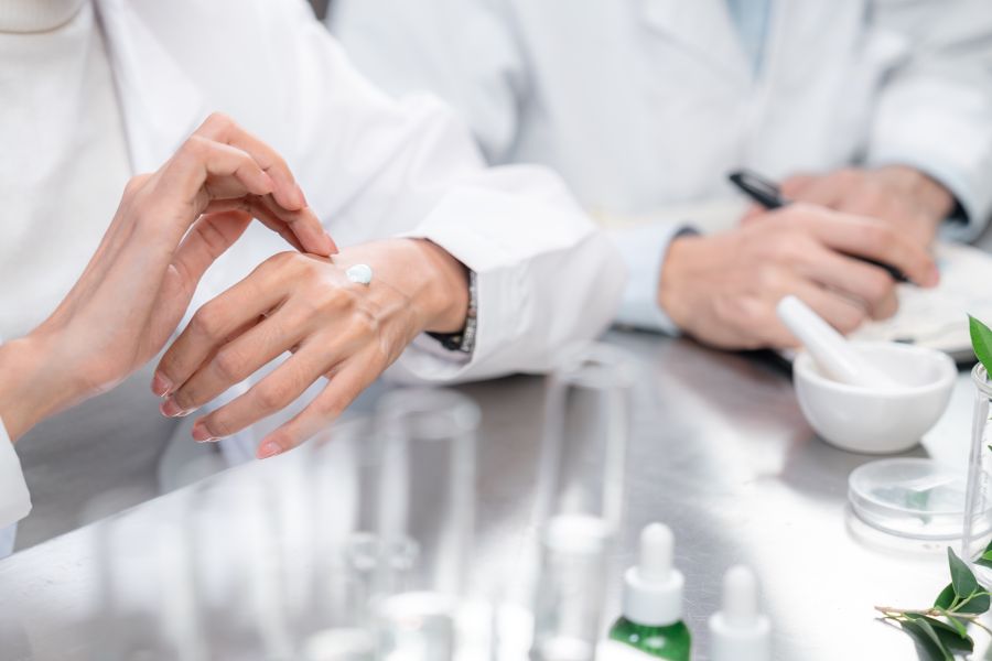 Scientists testing a cream on someone's hand. 
